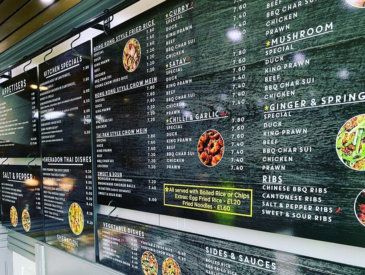 Dark hanging menu boards on a steel rail at Sheradon Grill & Wok Bar