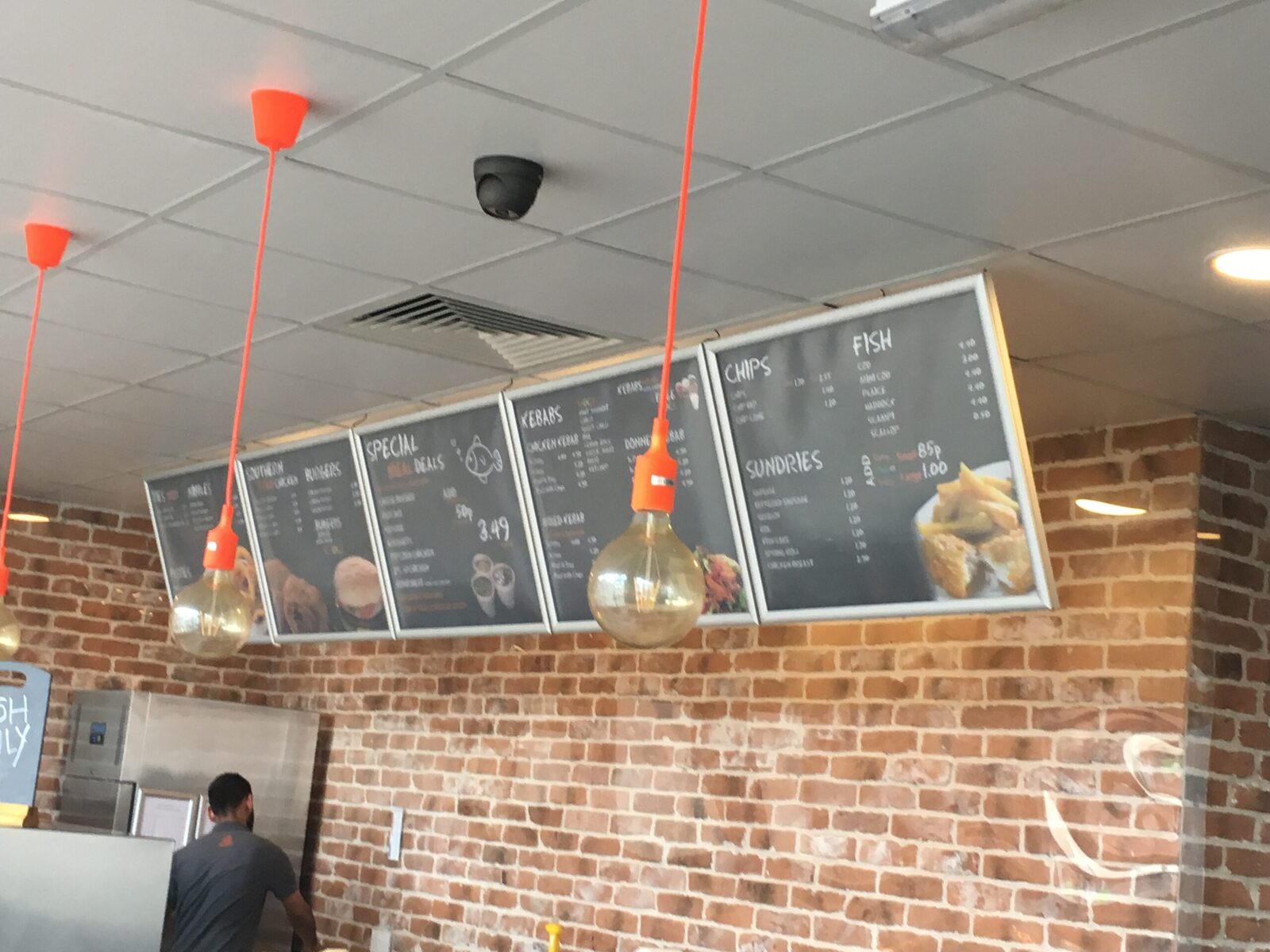 Chalkboard-style menu panels in white frames mounted over exposed brickwork