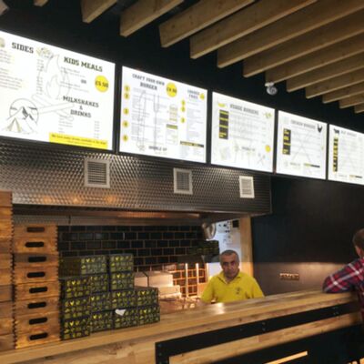 Yellow and white illuminated menu panels above a burger counter