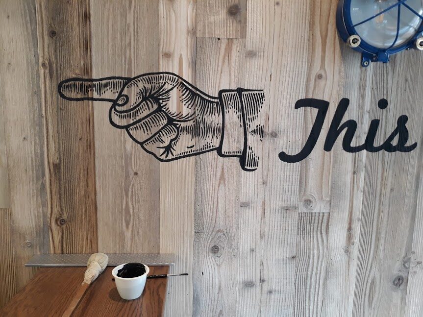 Hand-painted pointing hand and script lettering