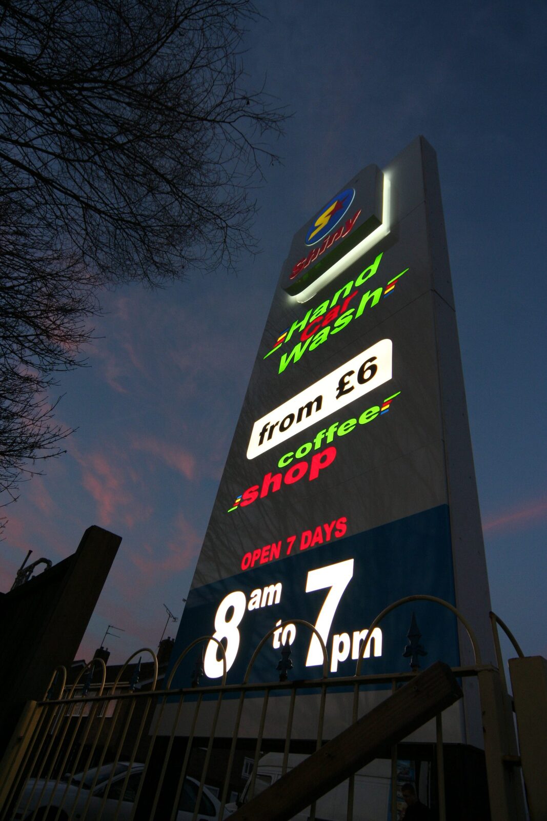 Illuminated roadside totem sign lit at dusk